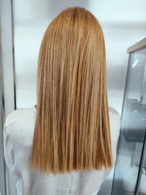 Donna con lunghi capelli castani lisci, in piedi in un interno. Indossa una camicia bianca.