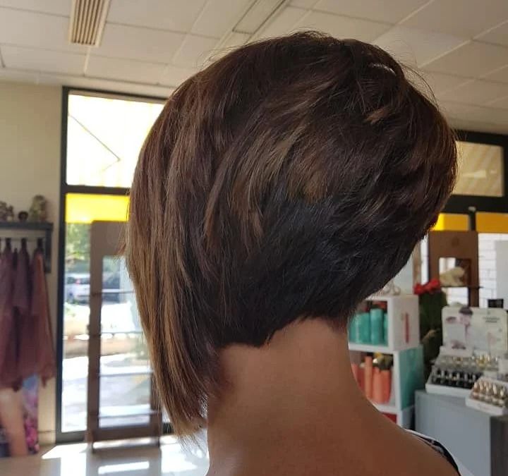 Vista posteriore di una donna con un taglio di capelli castano asimmetrico e scalato.
