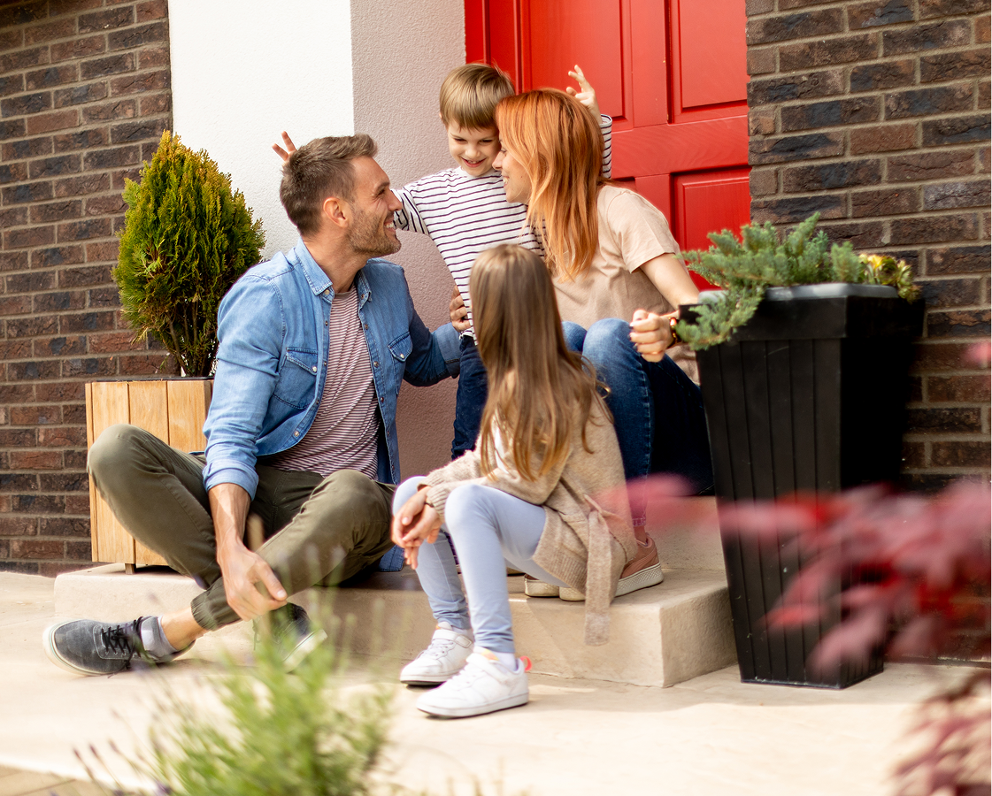 A family is sitting on the steps of their house.