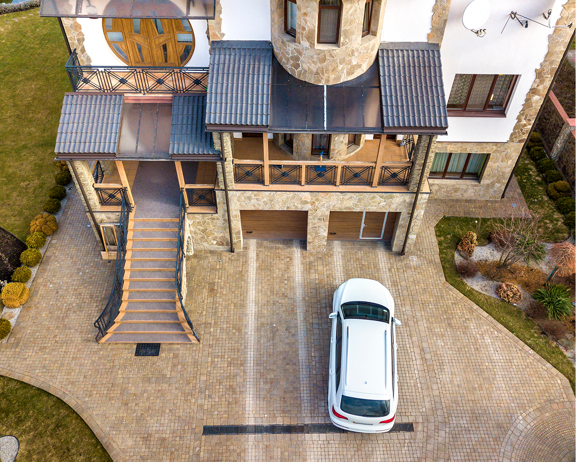 An aerial view of a car parked in front of a large house.
