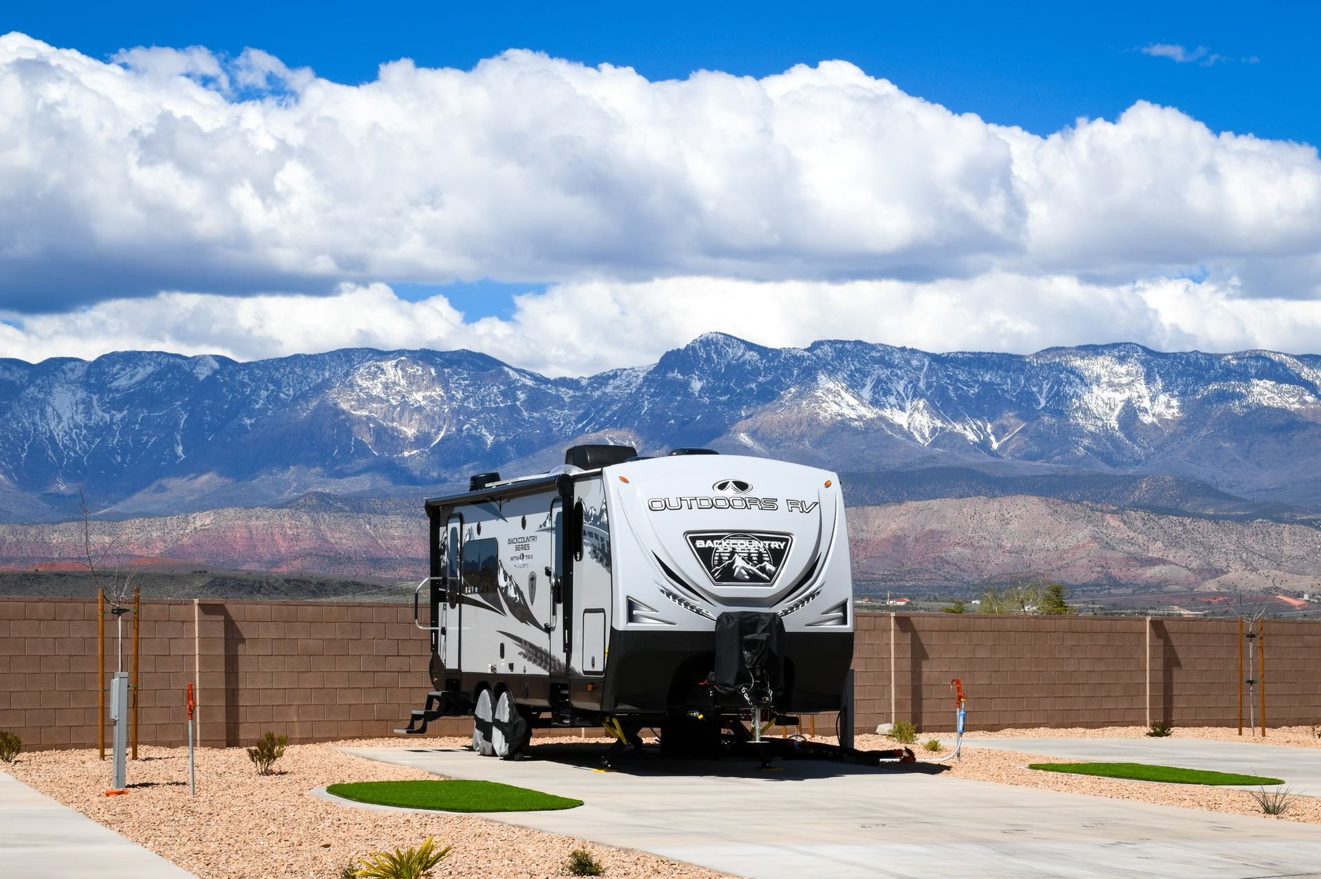 A rv is parked in a parking lot with mountains in the background.