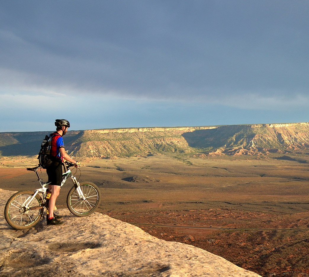 A man is riding a bike on top of a rocky hill.