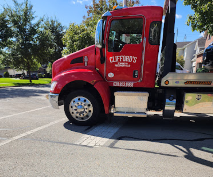A red tow truck from clifford 's is parked in a parking lot