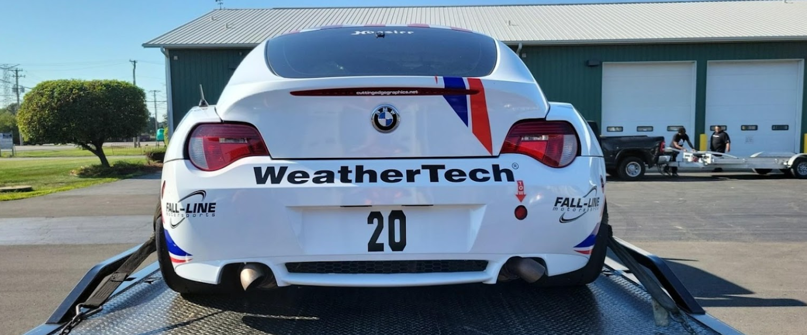 A white bmw is sitting on top of a tow truck.