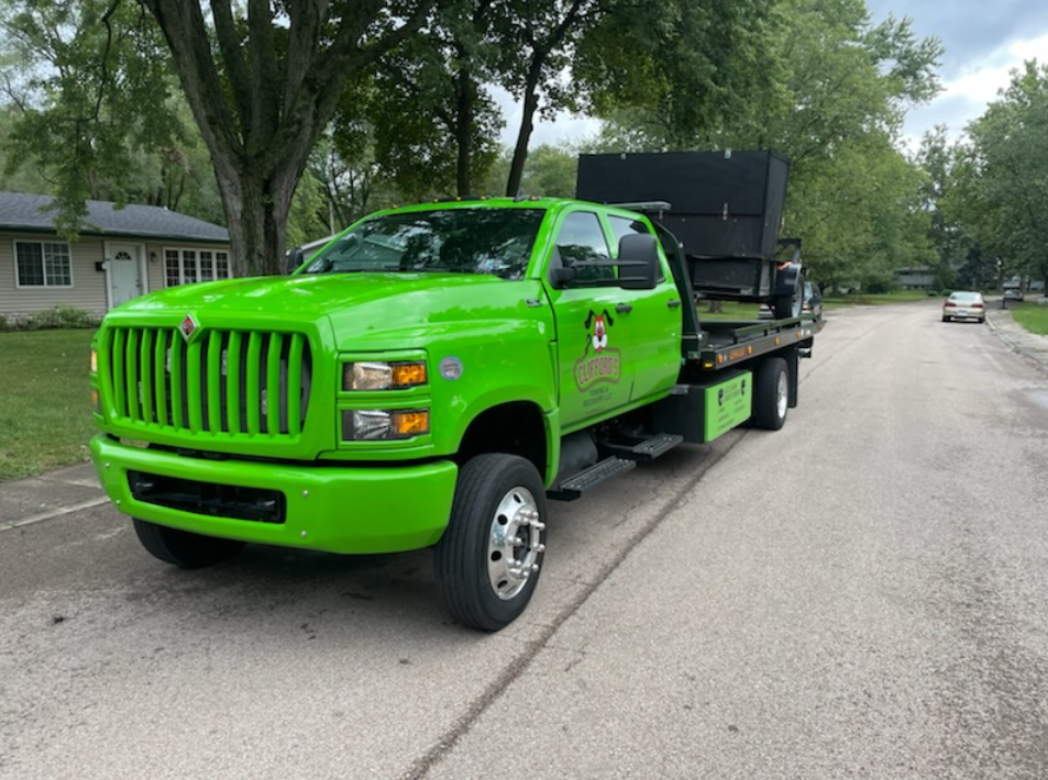 A green tow truck is parked on the side of the road.