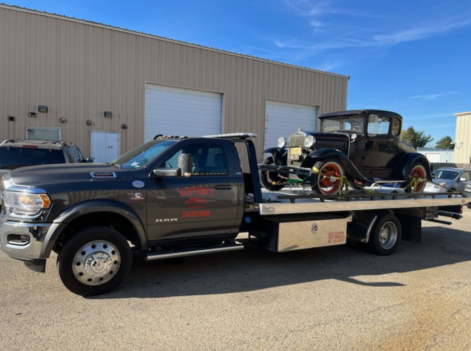 An old car is being towed by a tow truck.
