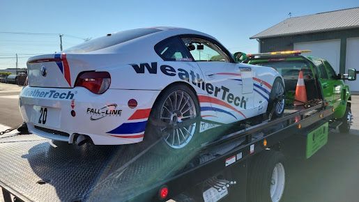 A race car is being towed by a tow truck.