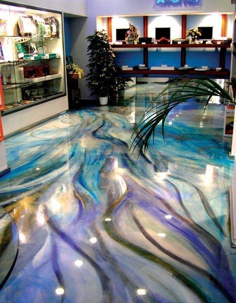 Construction workers in industrial hall applying grey epoxy resin to the floor to create a smooth and durable surface.