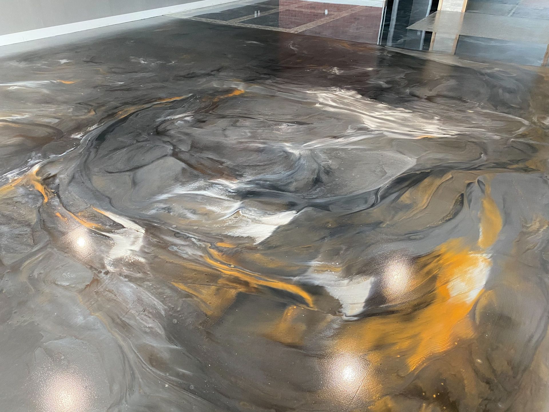 Construction workers in industrial hall applying grey epoxy resin to the floor to create a smooth and durable surface.