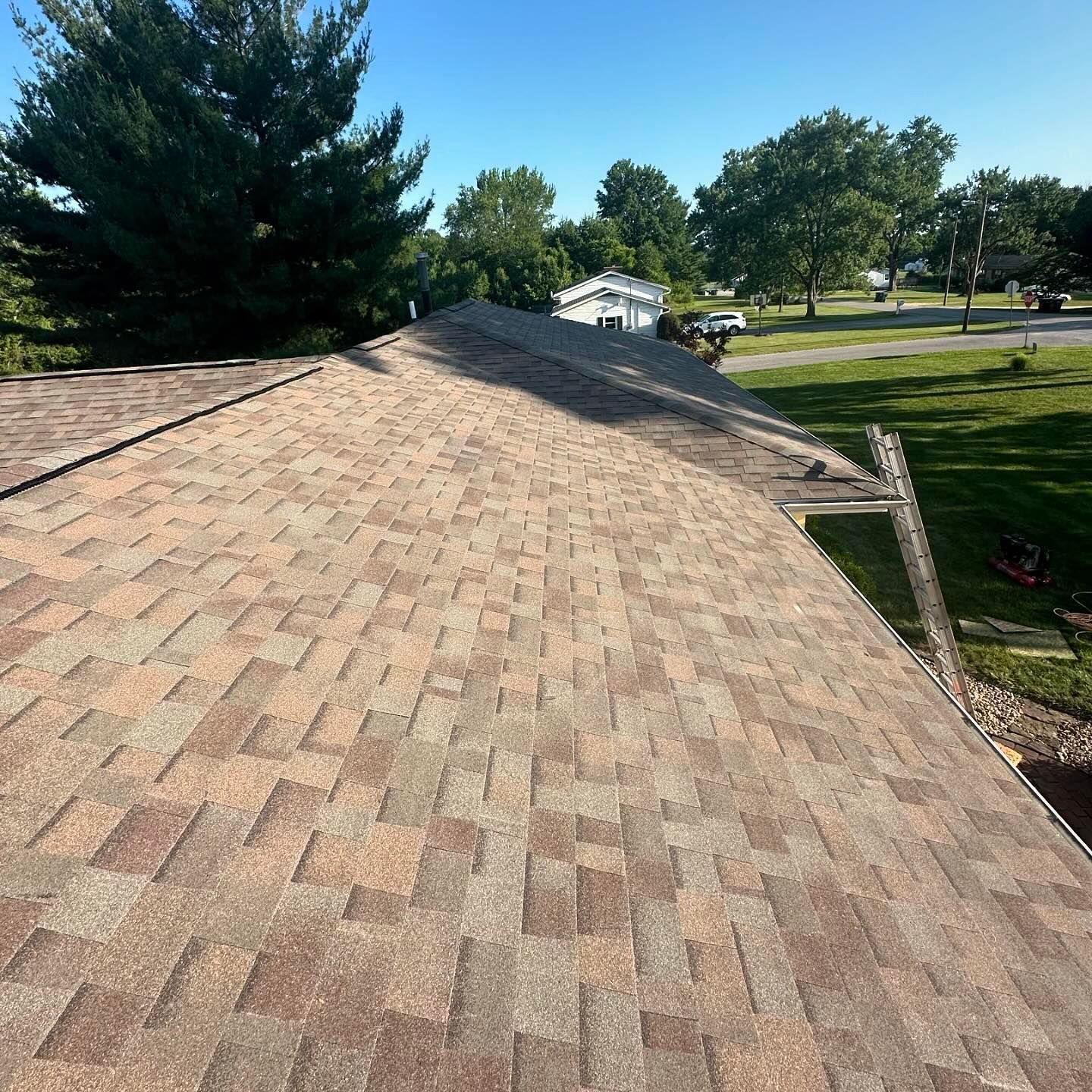 a man is sitting on the roof of a house .