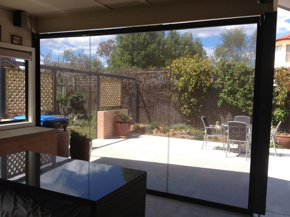 Patio with retractable black screen, concrete floor, backyard view through screen.