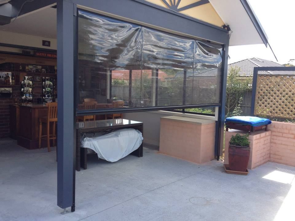 Patio with a table covered, roll-down shade, and a bar area.