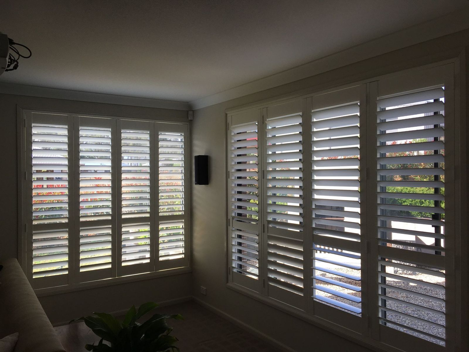 White shutters on windows in a room, partially open to allow light.