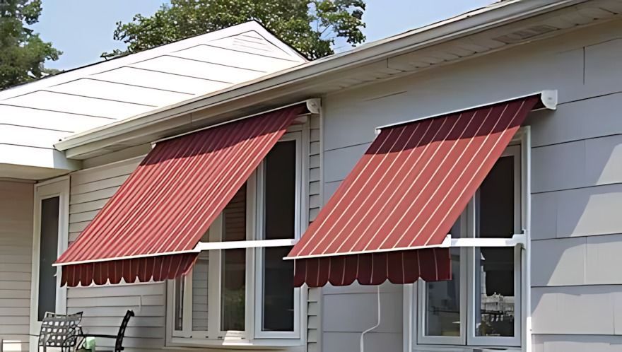 Red and white striped awnings above windows on a white house.
