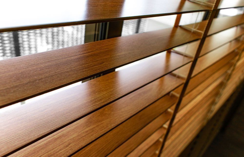Close-up view of wooden blinds, angled with visible window and light.