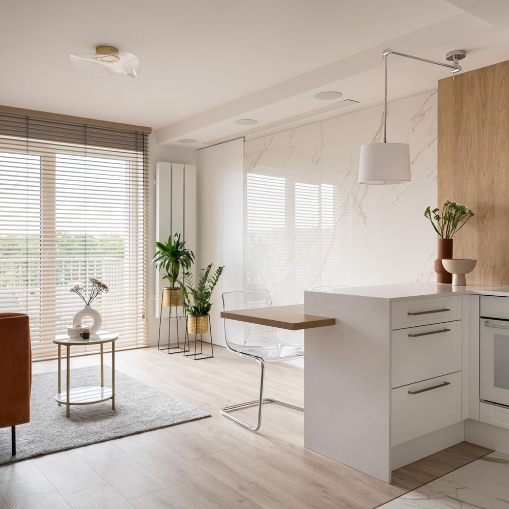 Bright, modern kitchen and living space with natural light, light wood flooring, and white and wooden accents.