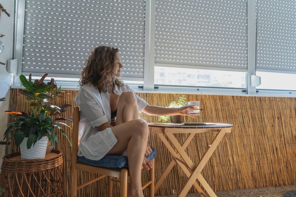 White shutters on a bay window in a bedroom, partially open, letting in light.