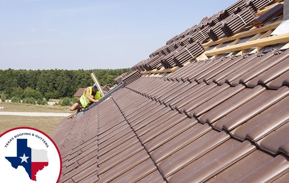 Roofers are installing a brown tile roof on a house