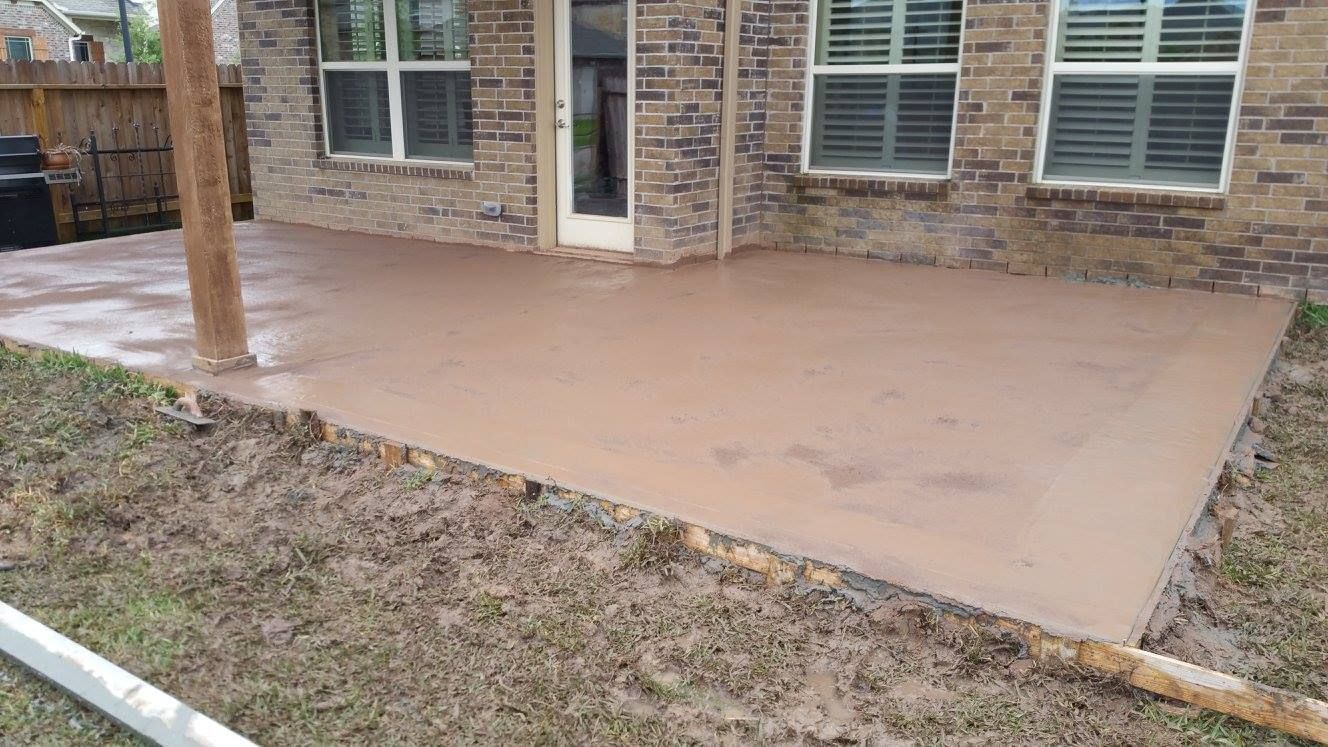 A muddy concrete patio next to a brick house with a wooden support beam.