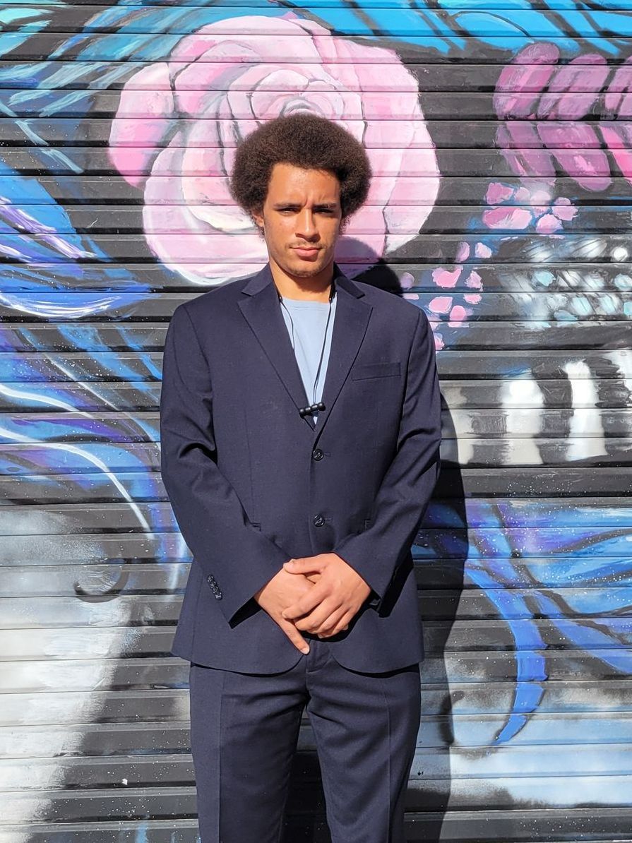 A man in a suit is standing in front of a graffiti wall.