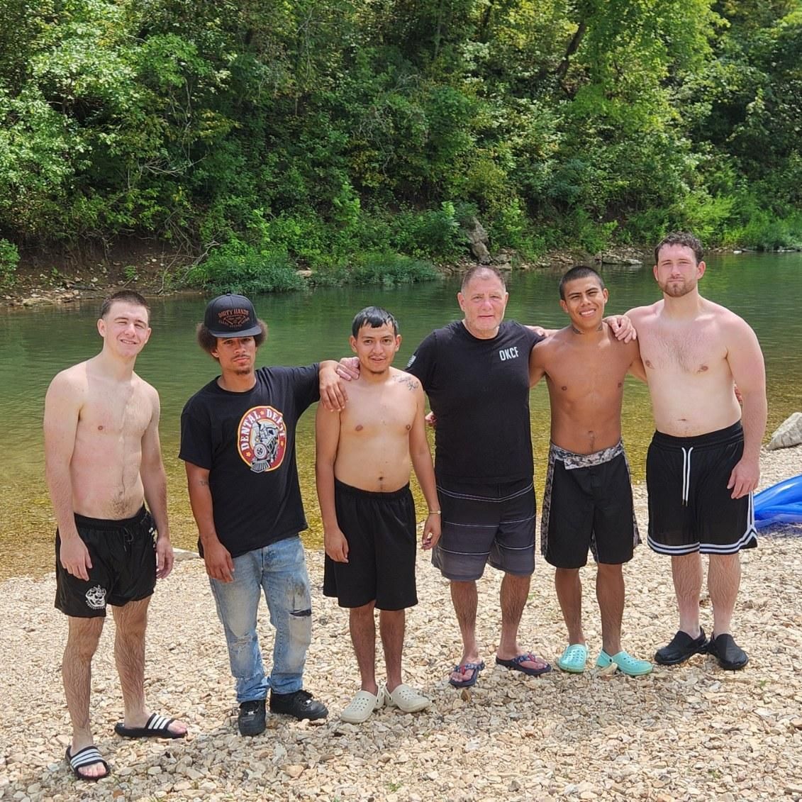 A group of men are posing for a picture in front of a river