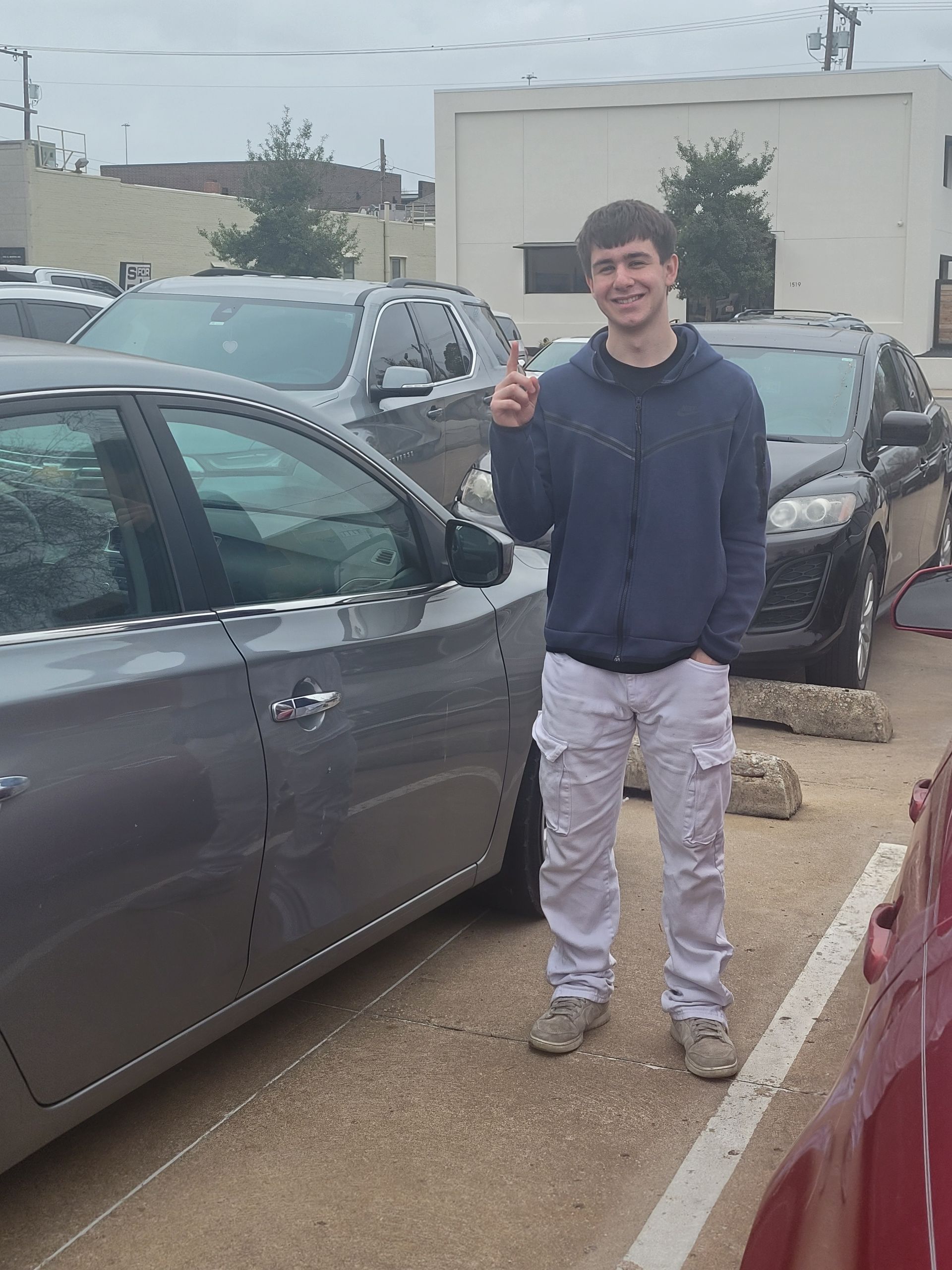 A young man is standing in front of a row of cars