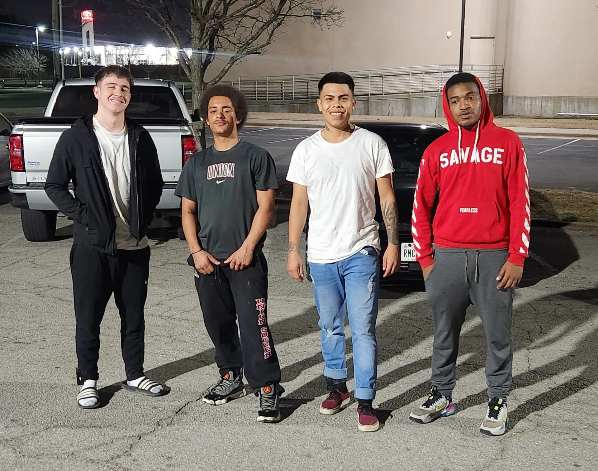 A group of young men are standing next to each other in a parking lot.