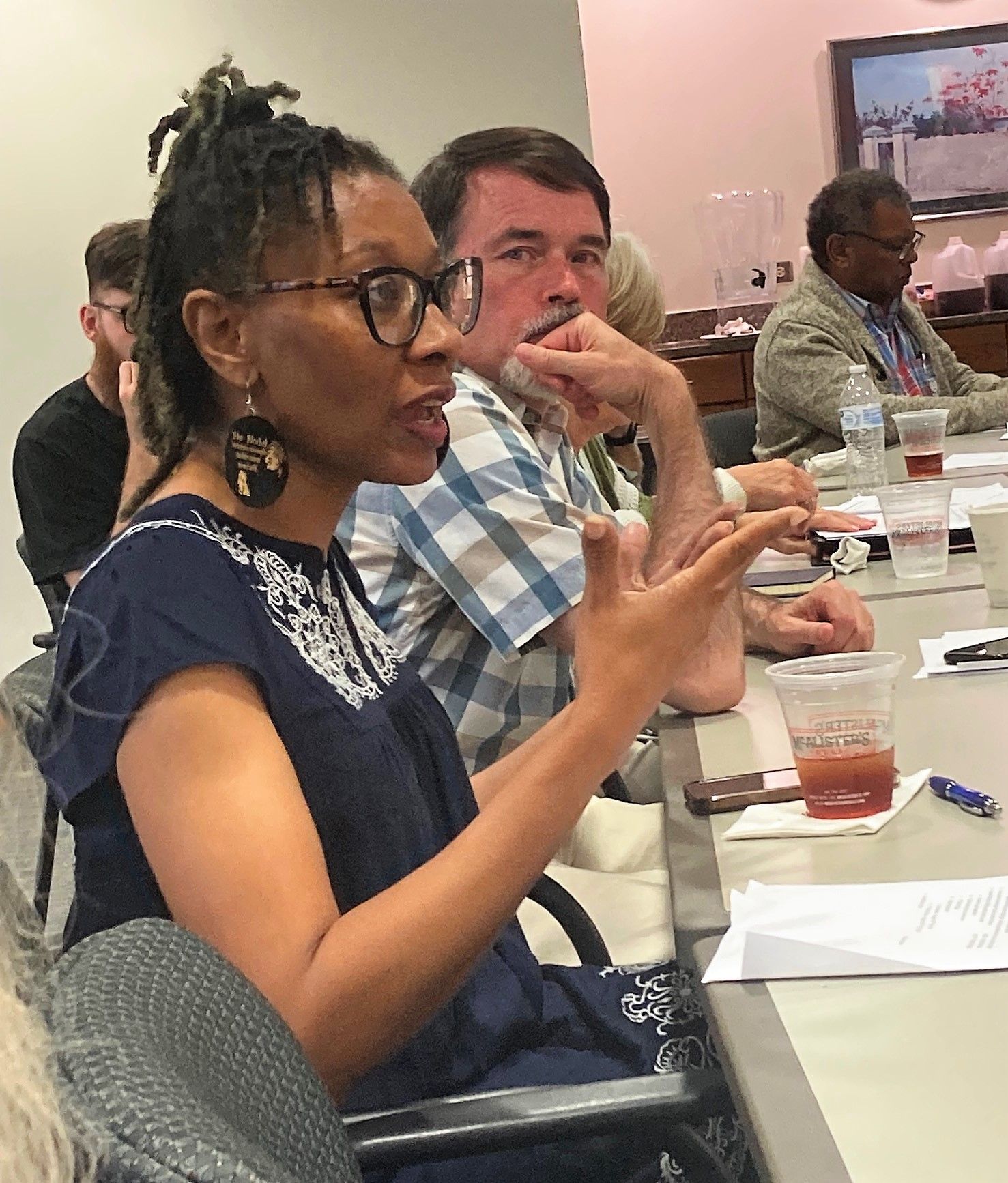 A woman wearing glasses is sitting at a table with other people