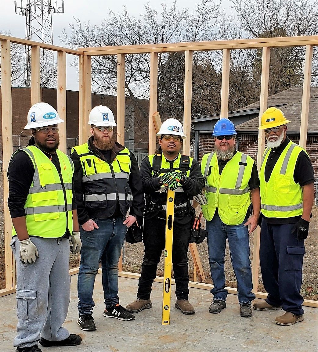 A group of construction workers are standing in front of a building under construction.