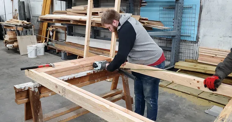 A man is working on a piece of wood in a workshop.
