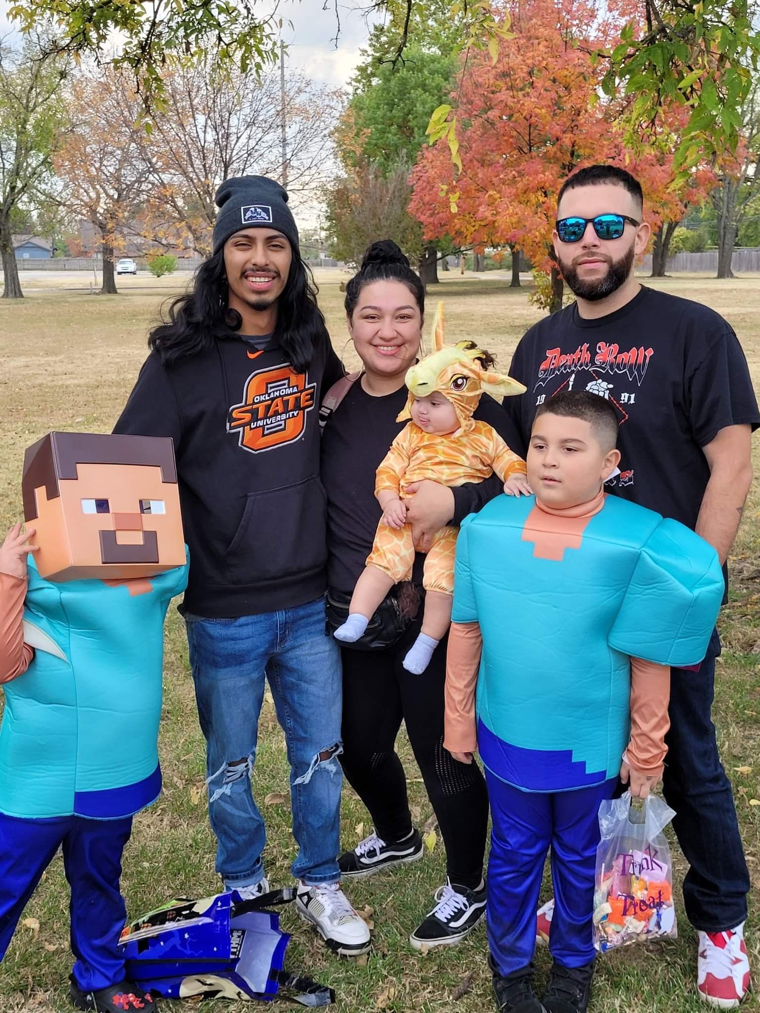 A group of people in costumes are posing for a picture in a park.