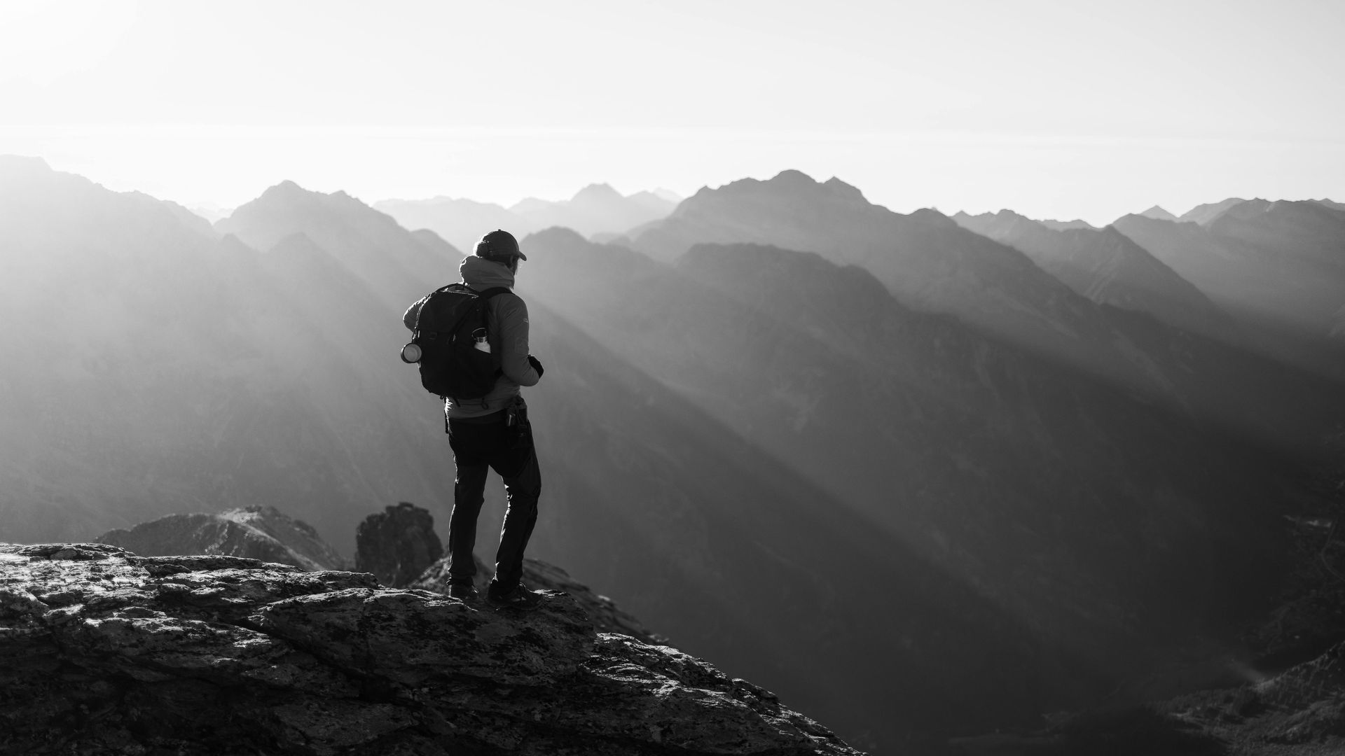 A man with a backpack is standing on top of a mountain.