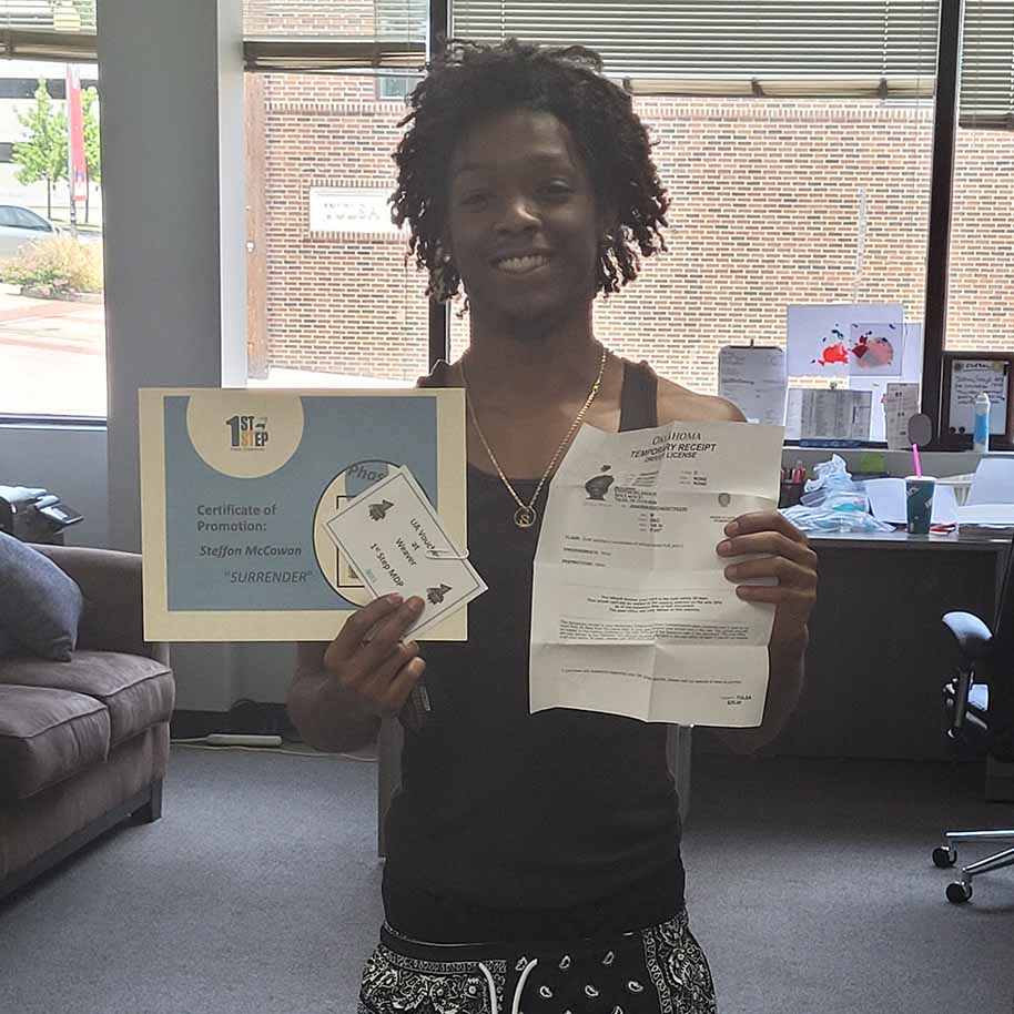 A man in a black tank top is holding a certificate and a piece of paper