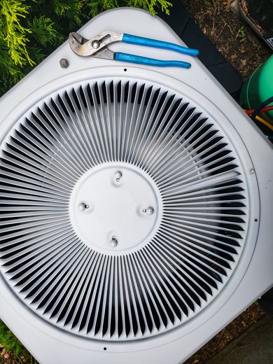 A pair of pliers sit on top of an air conditioner