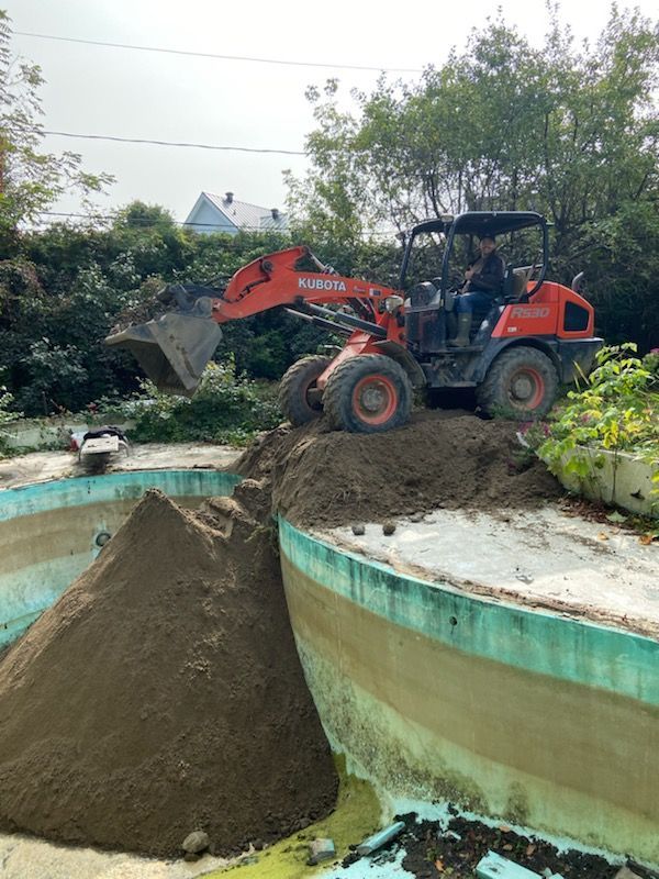 Un bulldozer déplace de la terre autour d'une piscine.