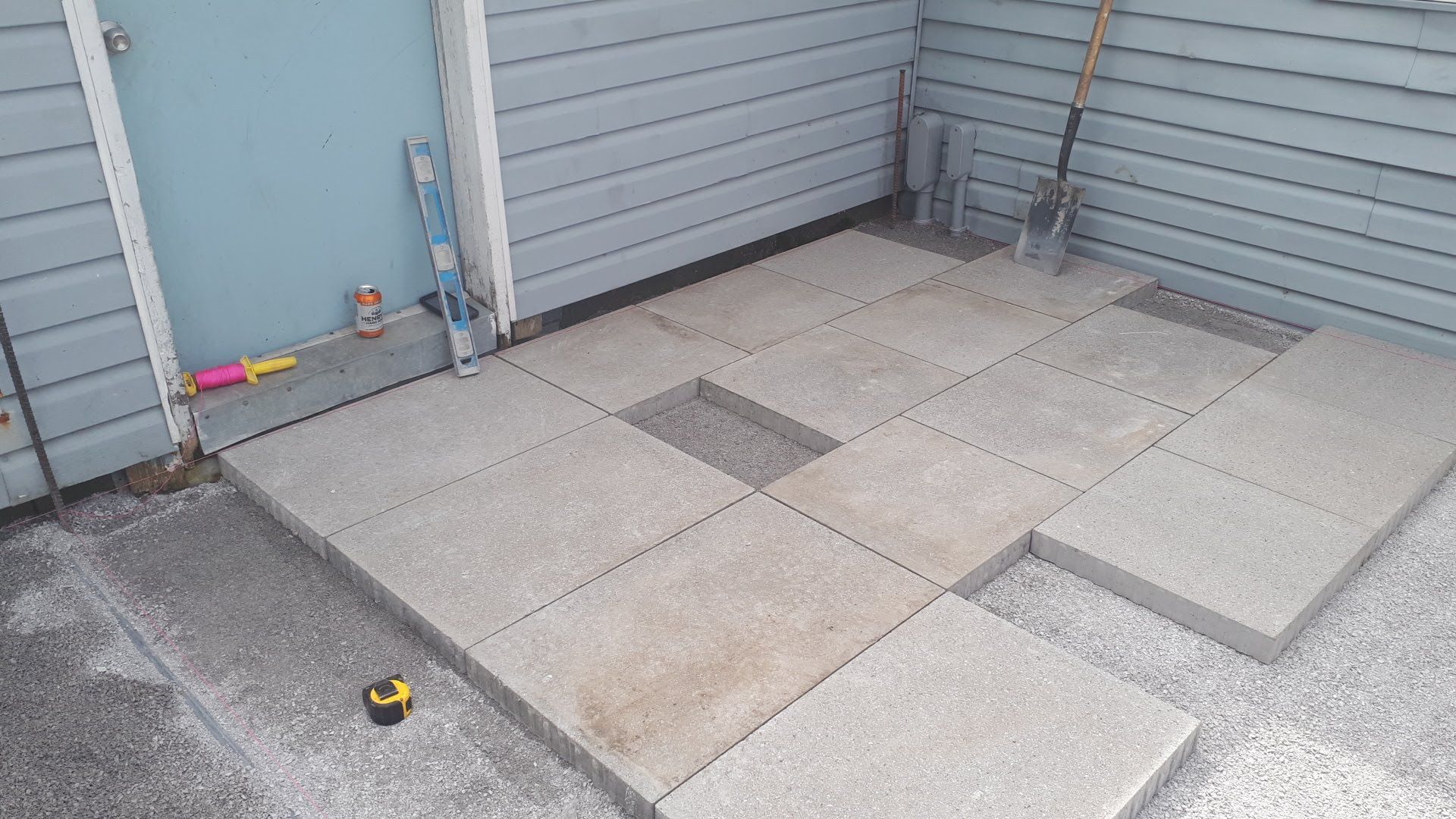 Un patio en béton est en cours de construction devant une maison.