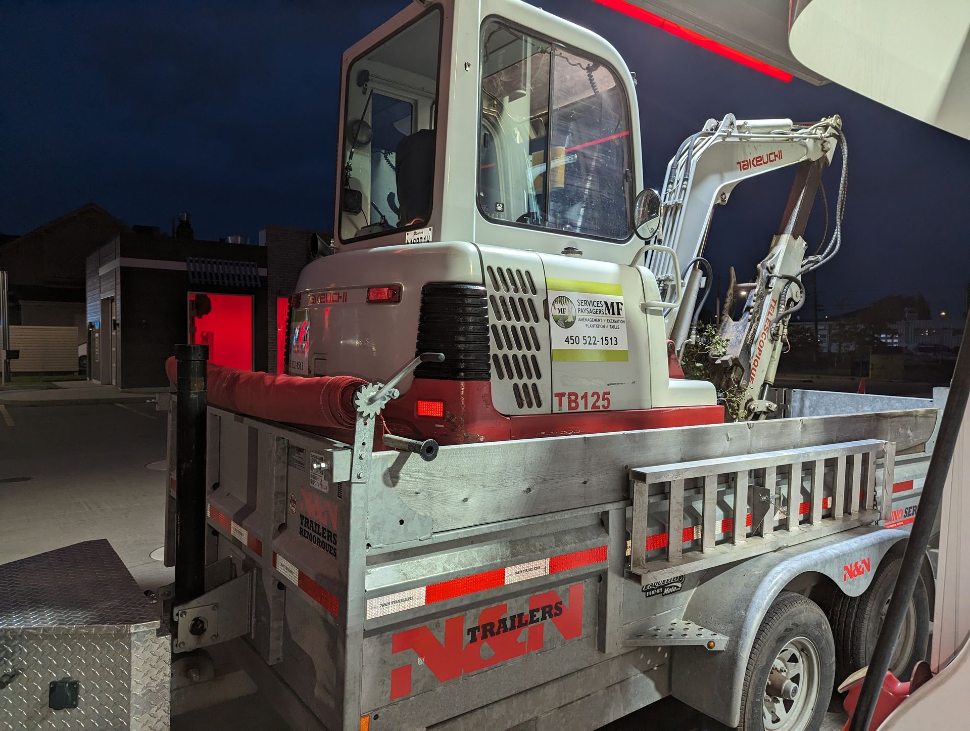 Une excavatrice est garée à l'arrière d'une remorque.