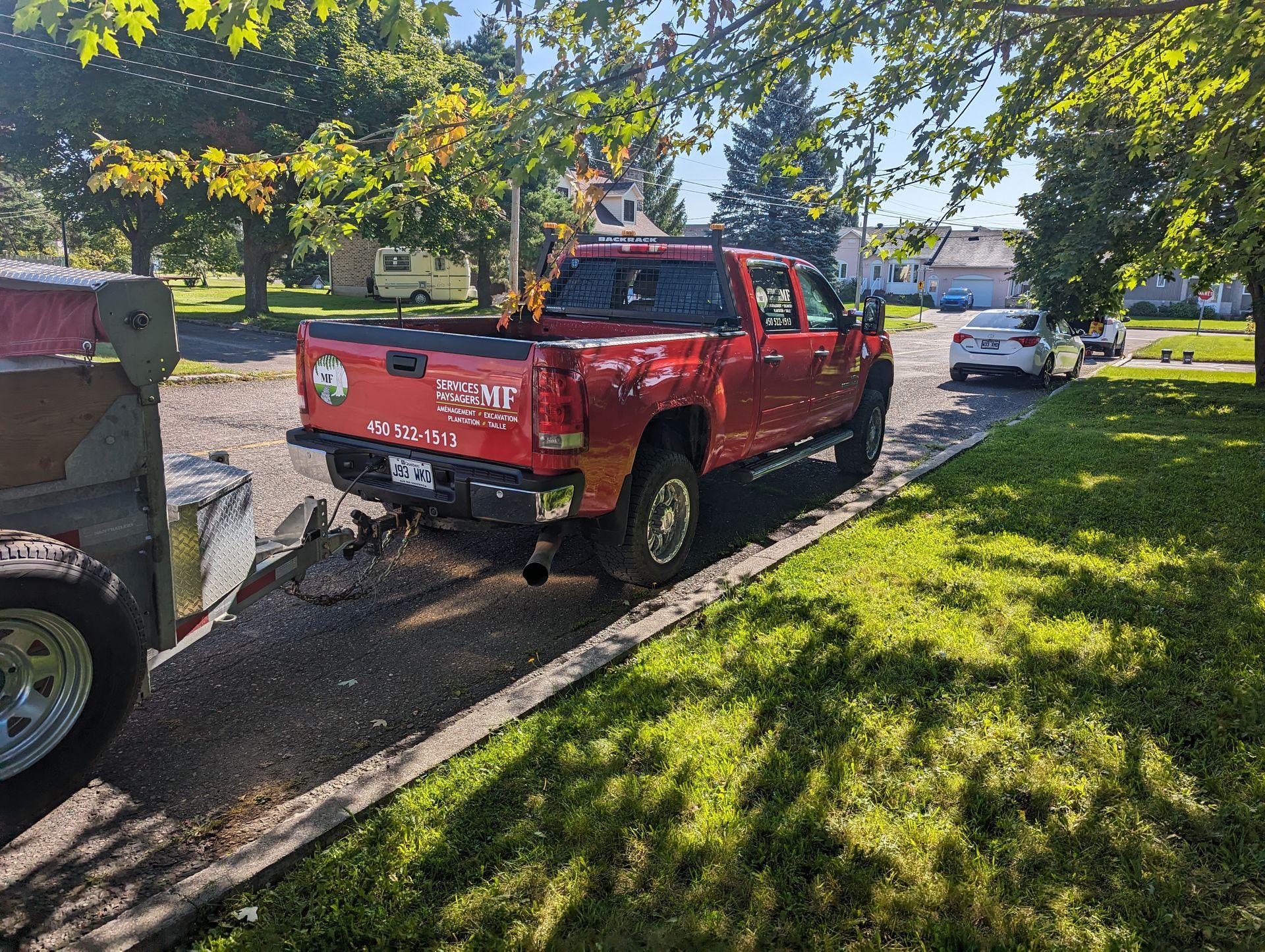 Un camion rouge est garé sur le bord de la route à côté d'une remorque.