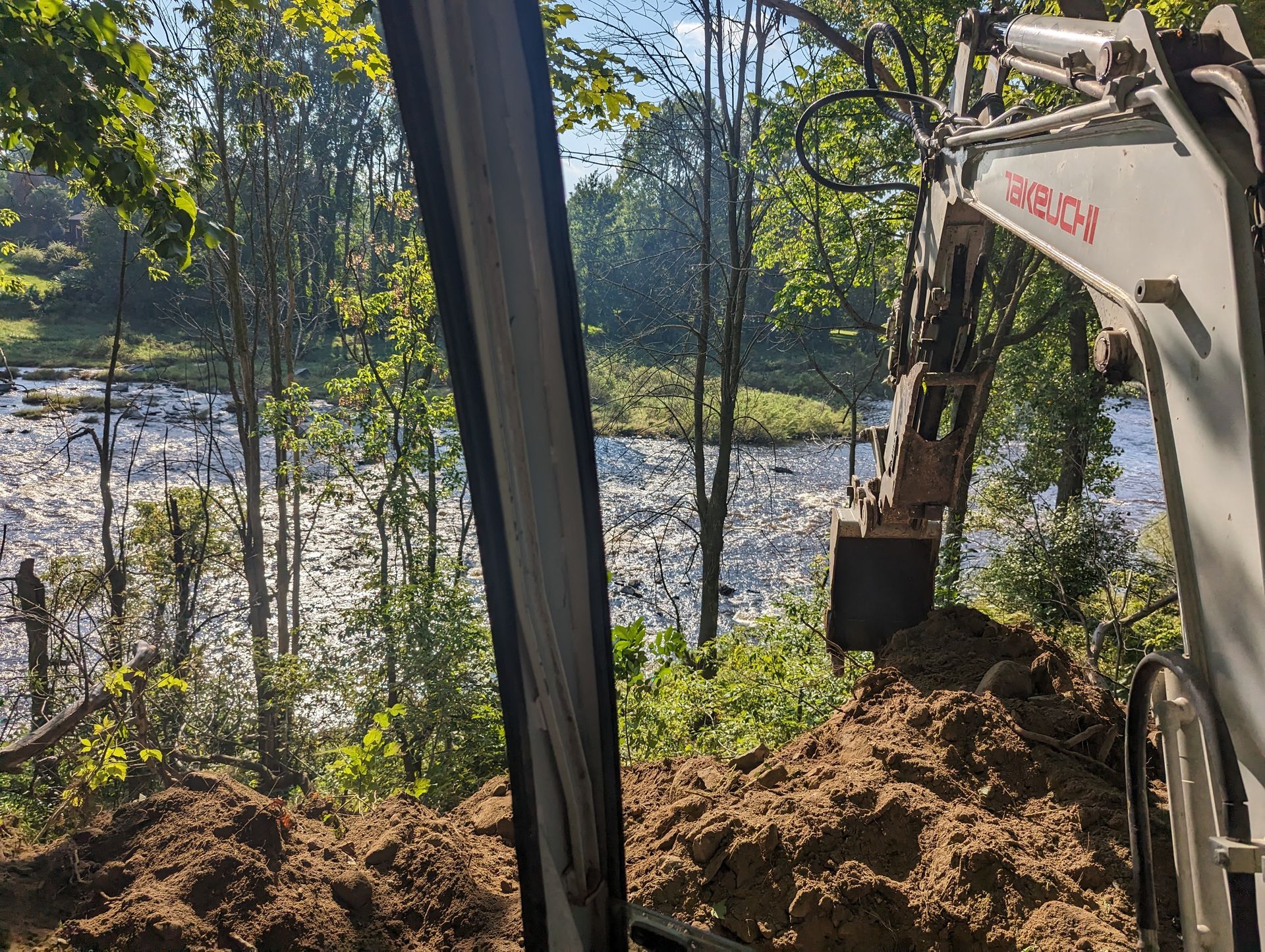 Une excavatrice creuse un trou dans le sol près d'une rivière.