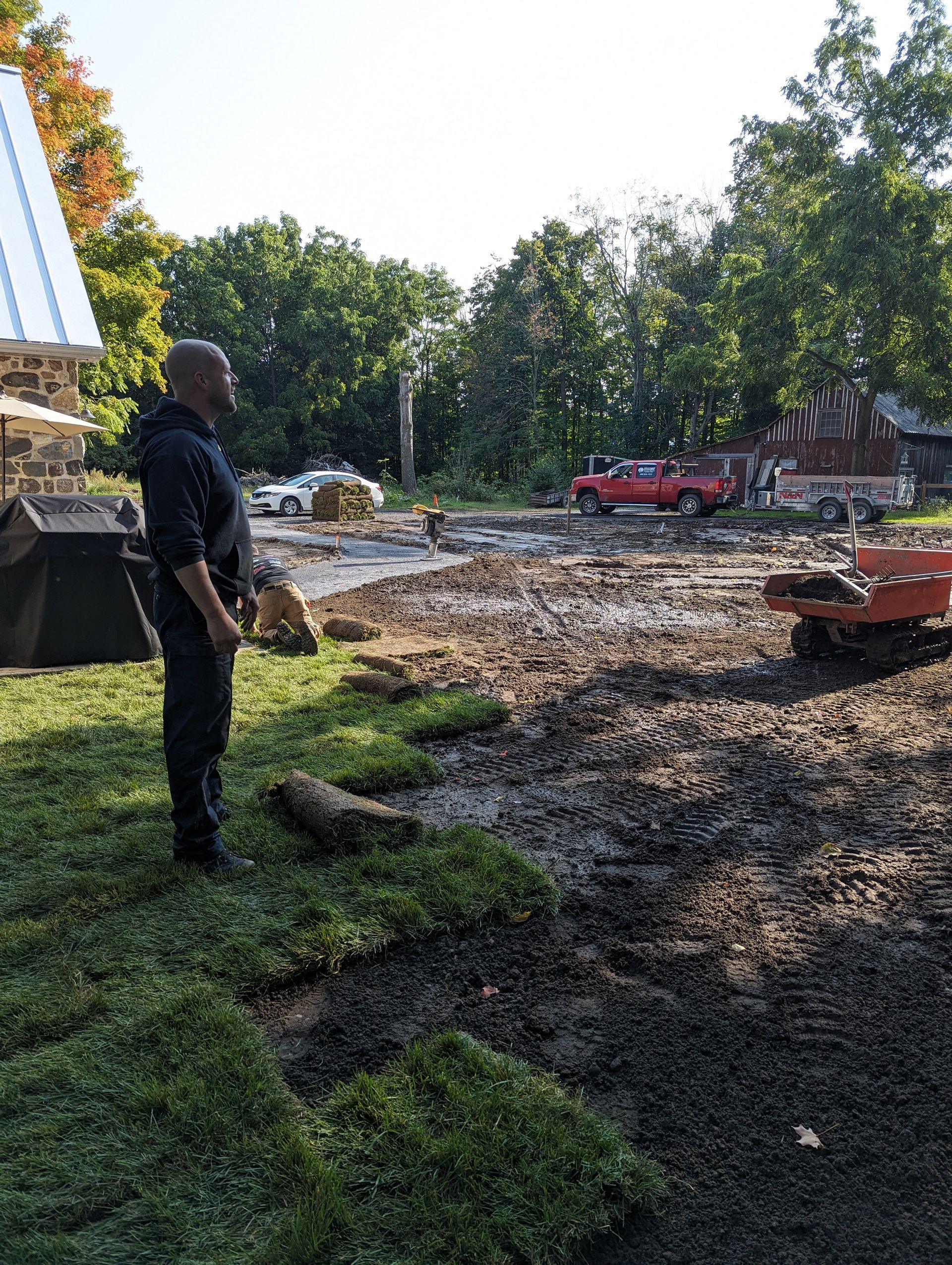 Un homme se tient à côté d’un tas d’herbe dans un champ de terre.