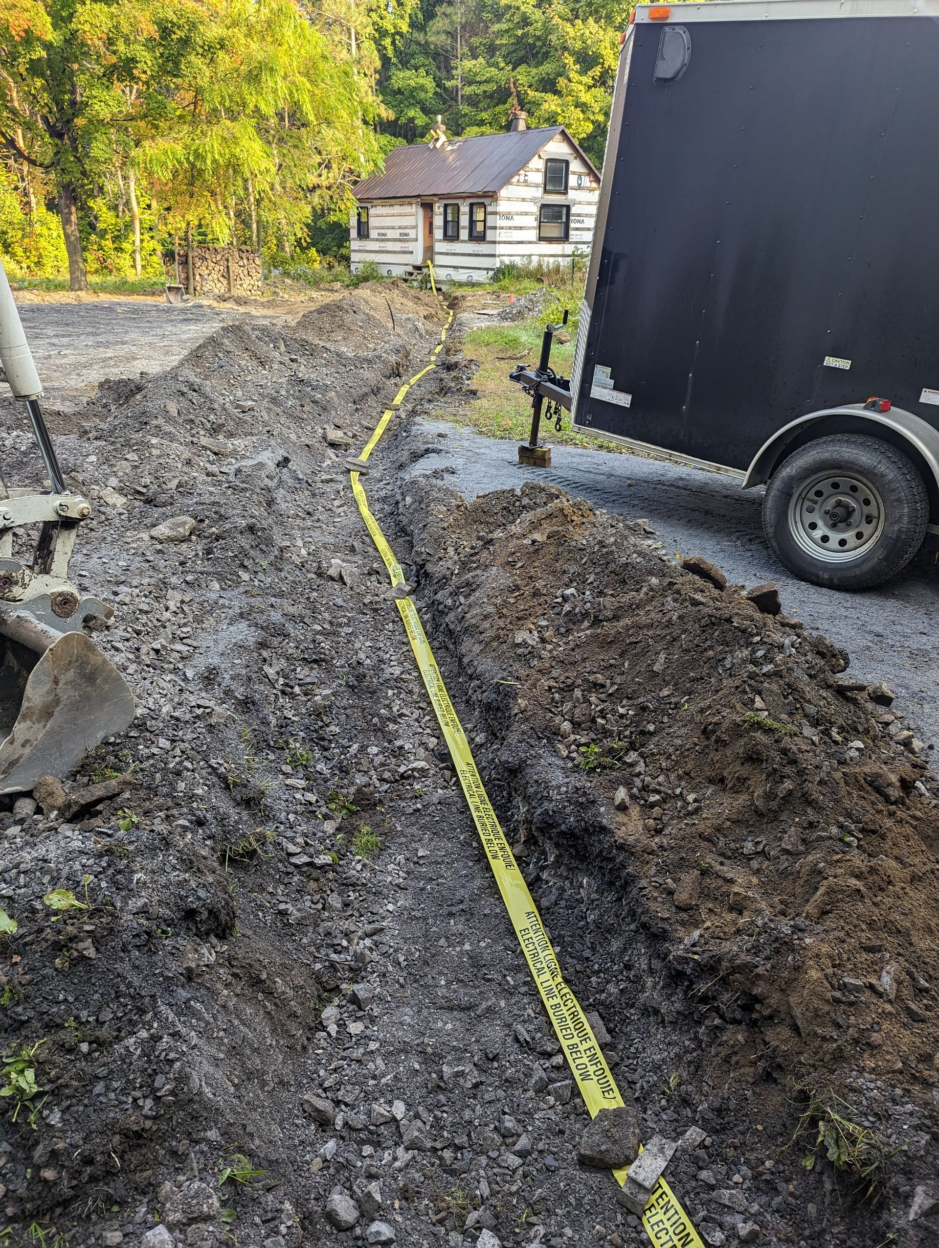 A black trailer is parked next to a large pile of dirt.