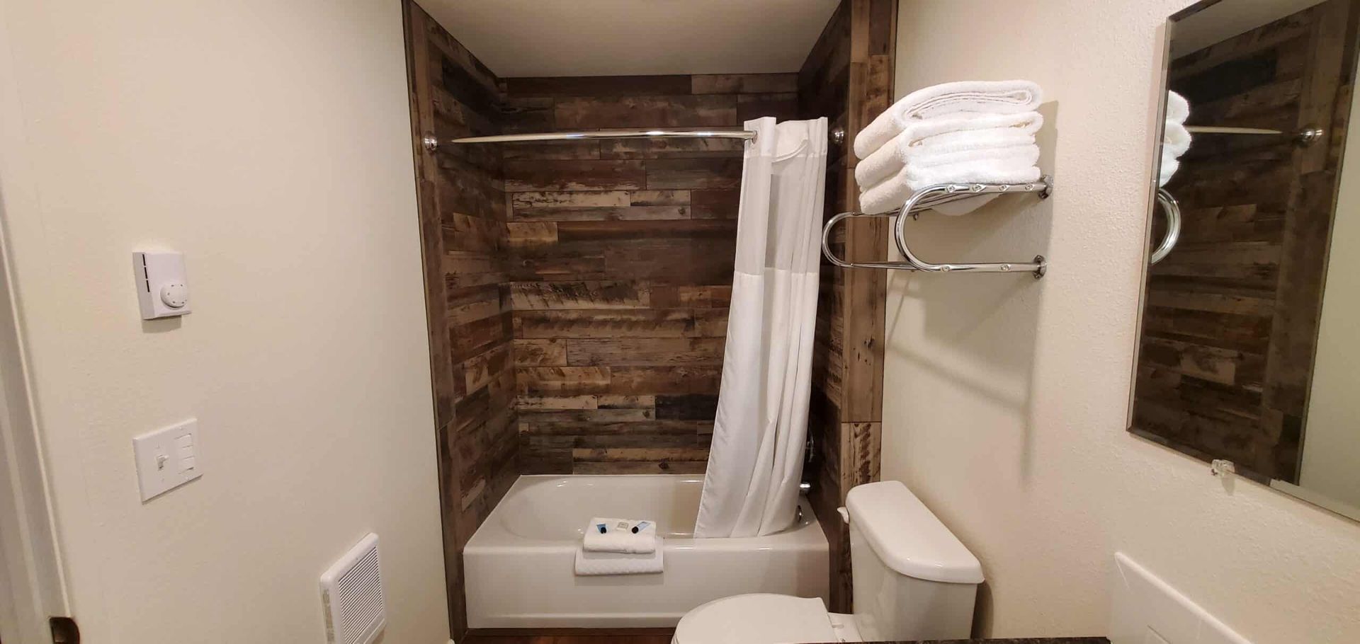 A bathroom with a toilet , tub , shower and mirror.