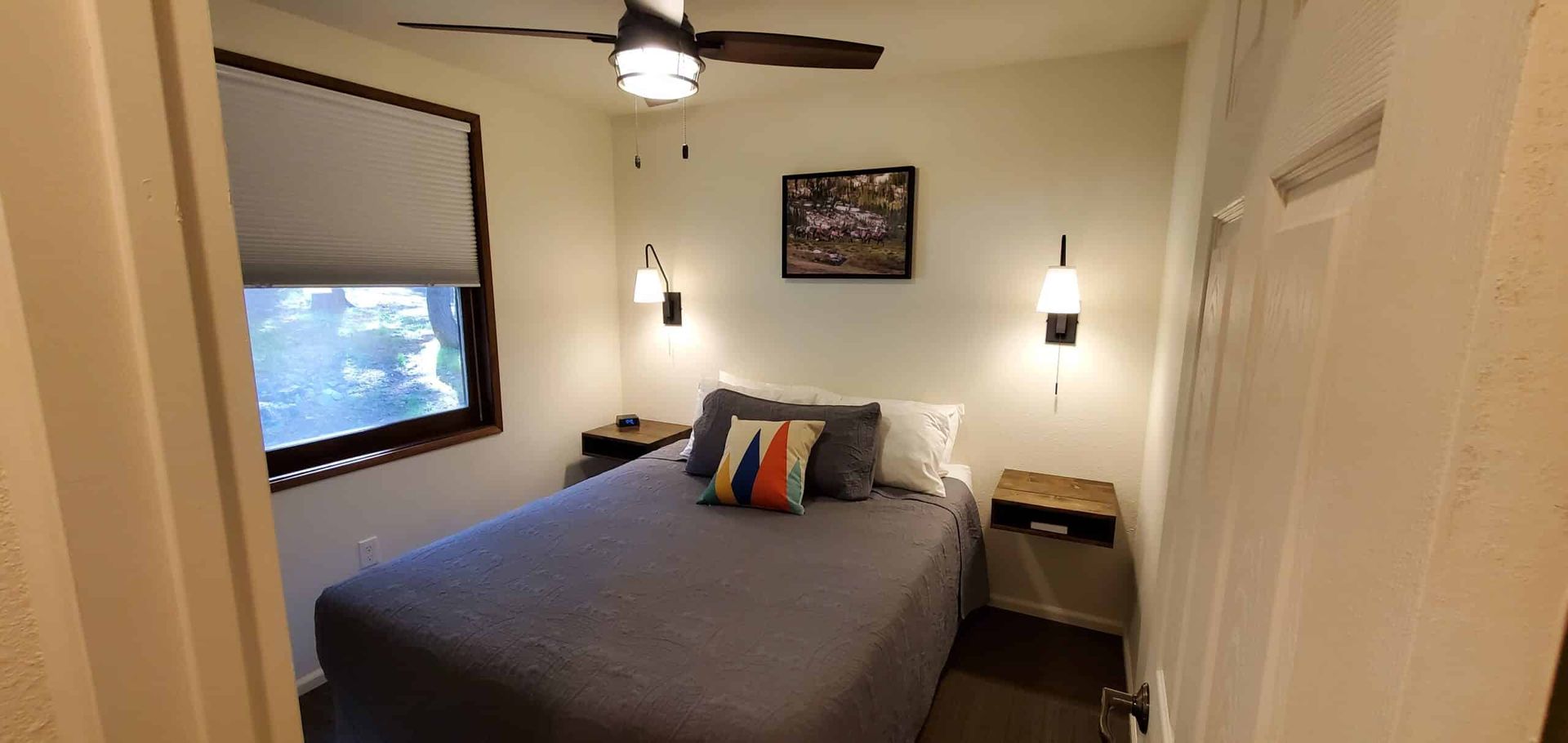 A bedroom with a bed and a ceiling fan.