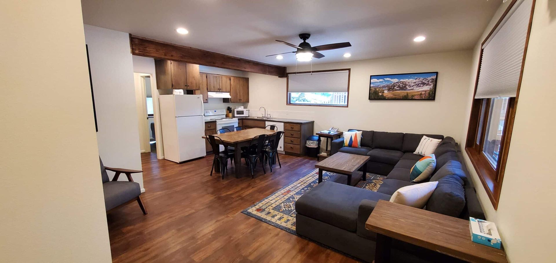 A living room with a couch , table , chairs and a ceiling fan.