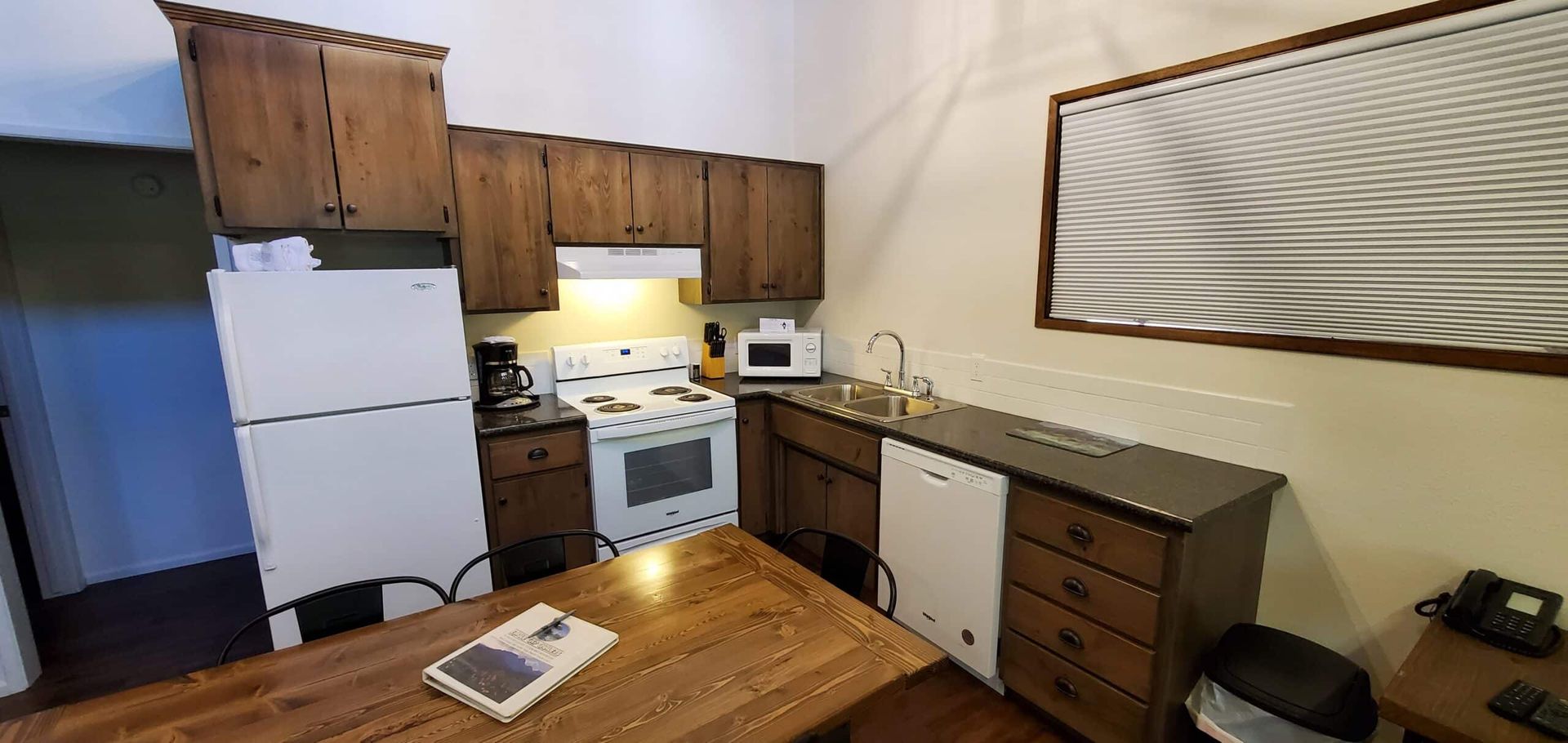 A kitchen with a table , refrigerator , stove , dishwasher , and sink.