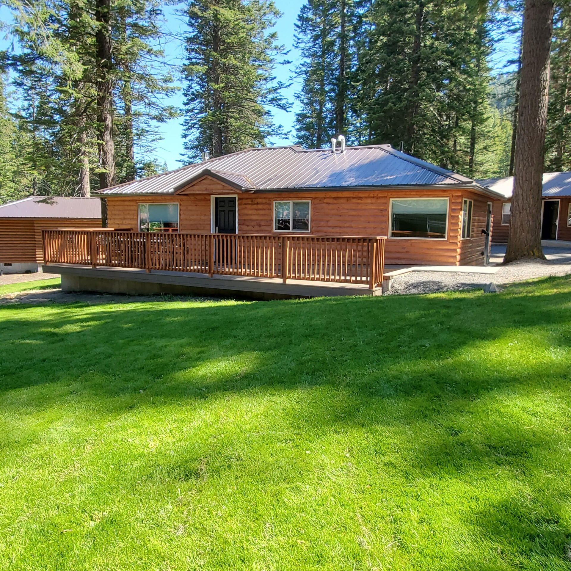 A house with a wooden deck and a lush green lawn in front of it.