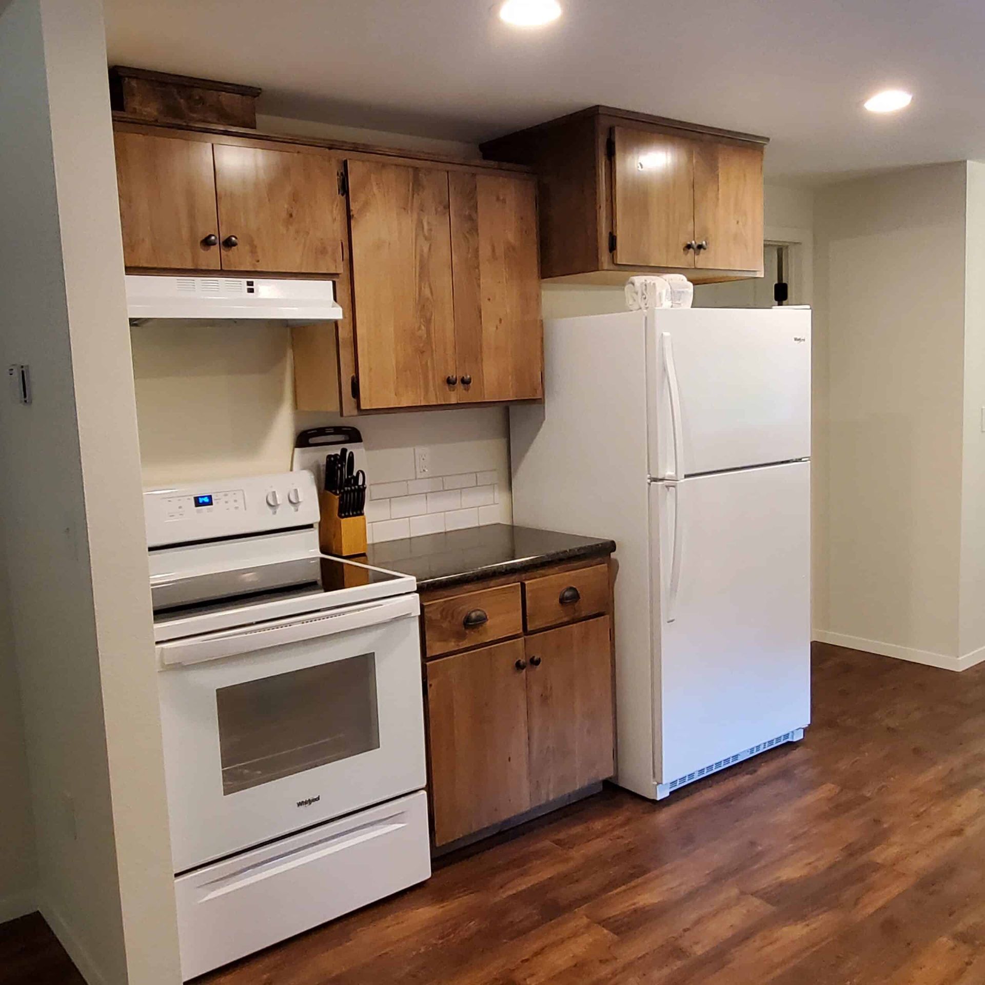 A kitchen with a stove , refrigerator , and cabinets.