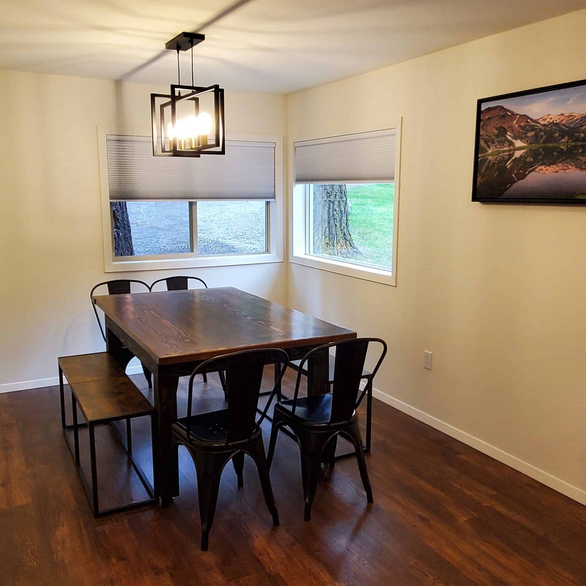 A dining room with a table and chairs and a picture on the wall