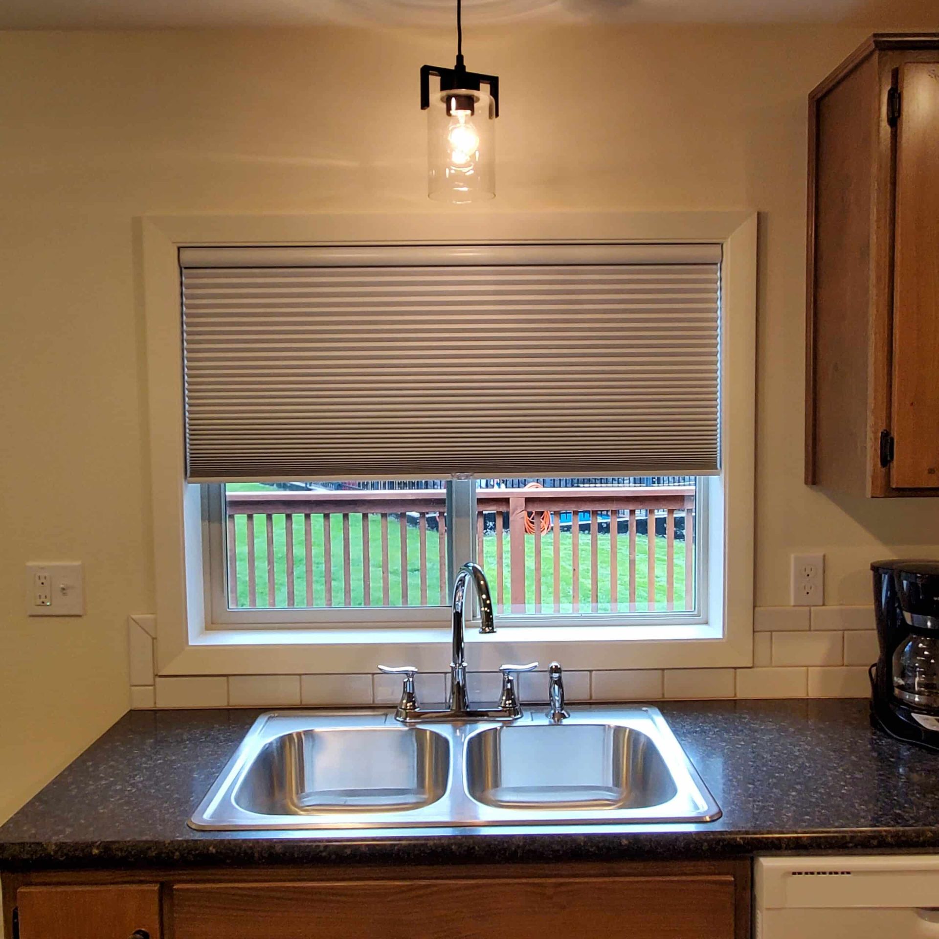 A kitchen with two sinks and a window with blinds