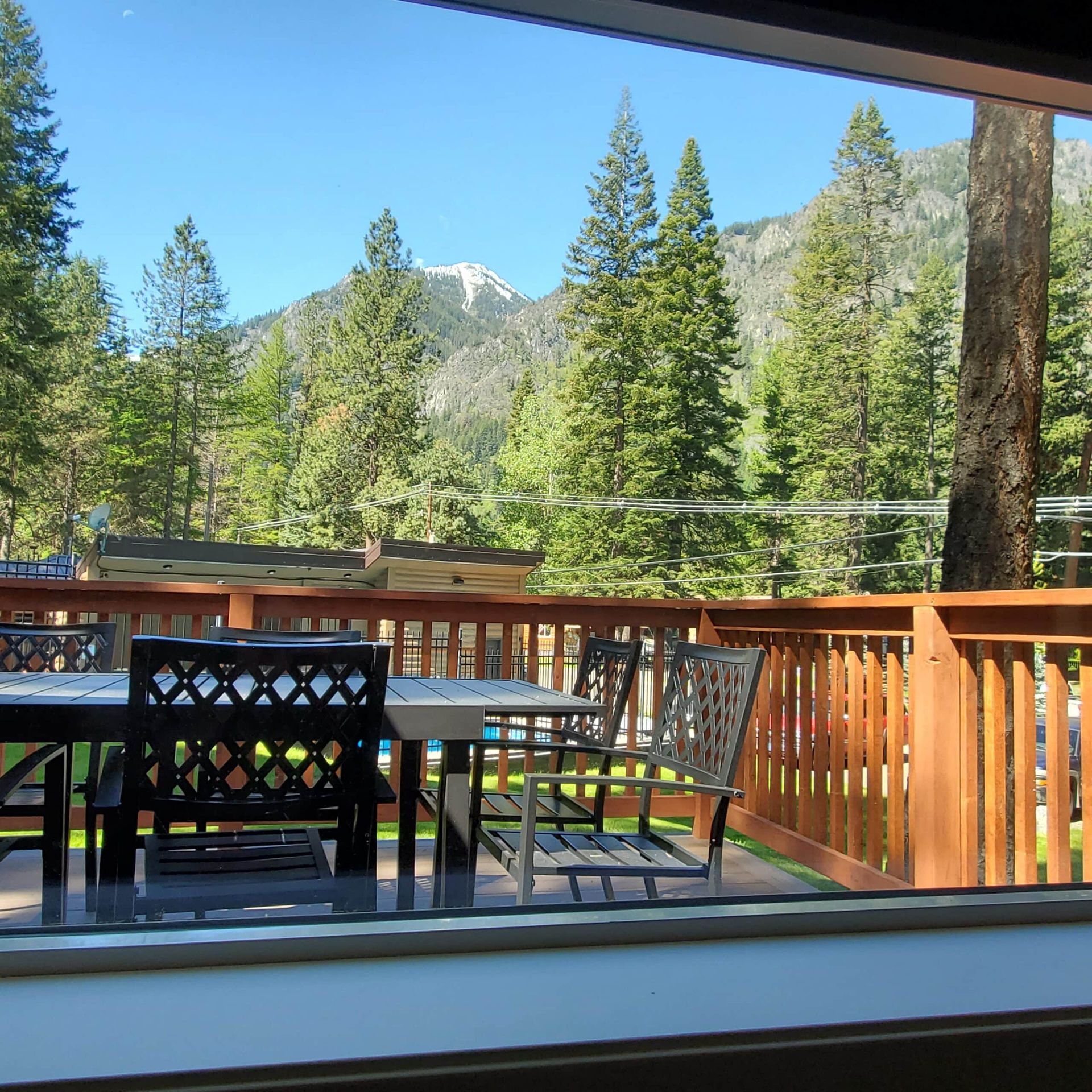 A table and chairs on a deck with mountains in the background